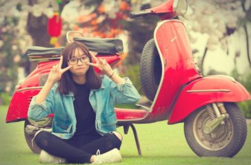 girl-doing-peace-sign-indian-sitting-in-front-of-red-scooter-motorcycle-881590/